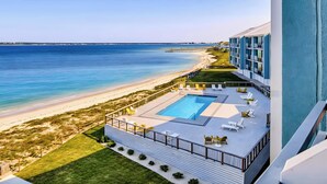 Un hôtel doté d’une piscine, offrant une vue sur la plage et disposant d’une terrasse avec des chaises longues.