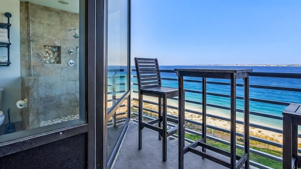 Un balcon avec vue sur l’océan, une douche en verre et un fauteuil.