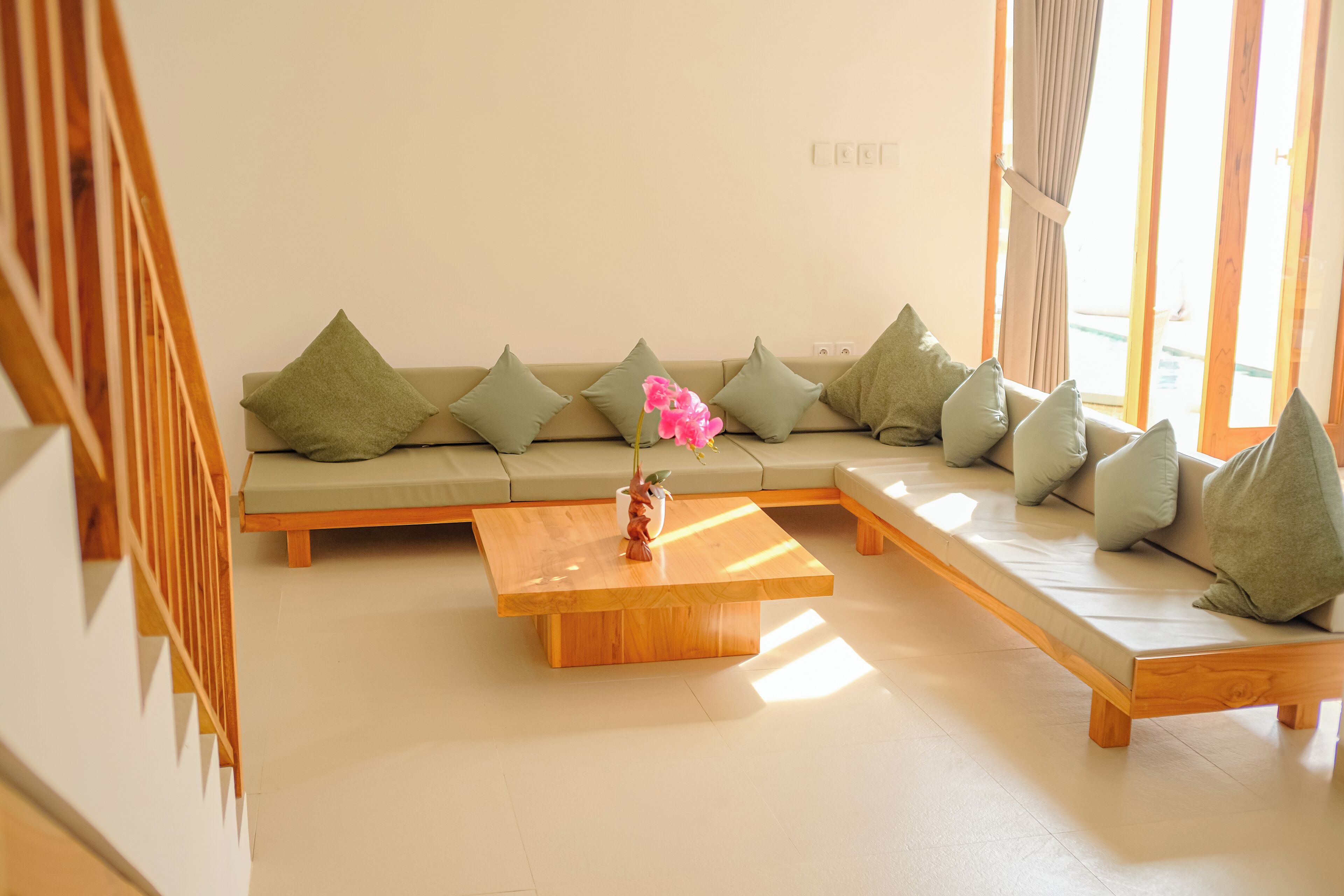A modern living room with a sectional sofa, a wooden coffee table, and a decorative vase with flowers.