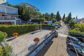 A residential street with a blue building, stone-paved walkway, and potted plants. - Apartment for 2 persons with sea view (Crikvenica)