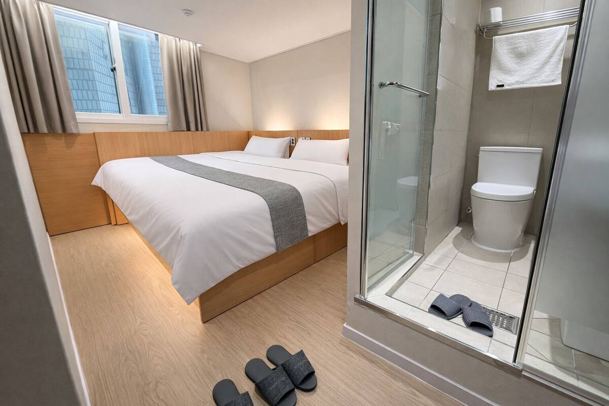 A hotel room with a bed, a shower, and a view of the city.