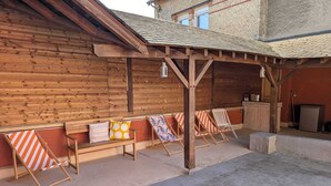 A wooden building with a covered patio area, a bench, and beach chairs. - Particulier rémois proche Cathédrale avec parking et terrasse (Reims)