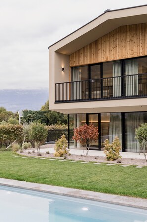 Une maison moderne à deux étages, dotée d’un balcon, d’une piscine et offrant une vue sur l’océan.