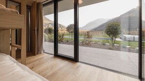 Ein Zimmer mit großem Fenster, Etagenbett und Blick auf eine Straße und Berge.