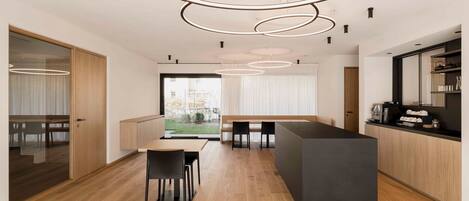 A modern kitchen with a central island, wooden flooring, and pendant lighting.