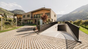 Ein modernes, zweistöckiges Haus mit flachem Dach, großen Fenstern und einer gepflasterten Auffahrt.
