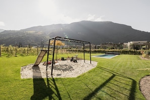 Ein Garten mit Schaukel, Sandkasten und Pool.