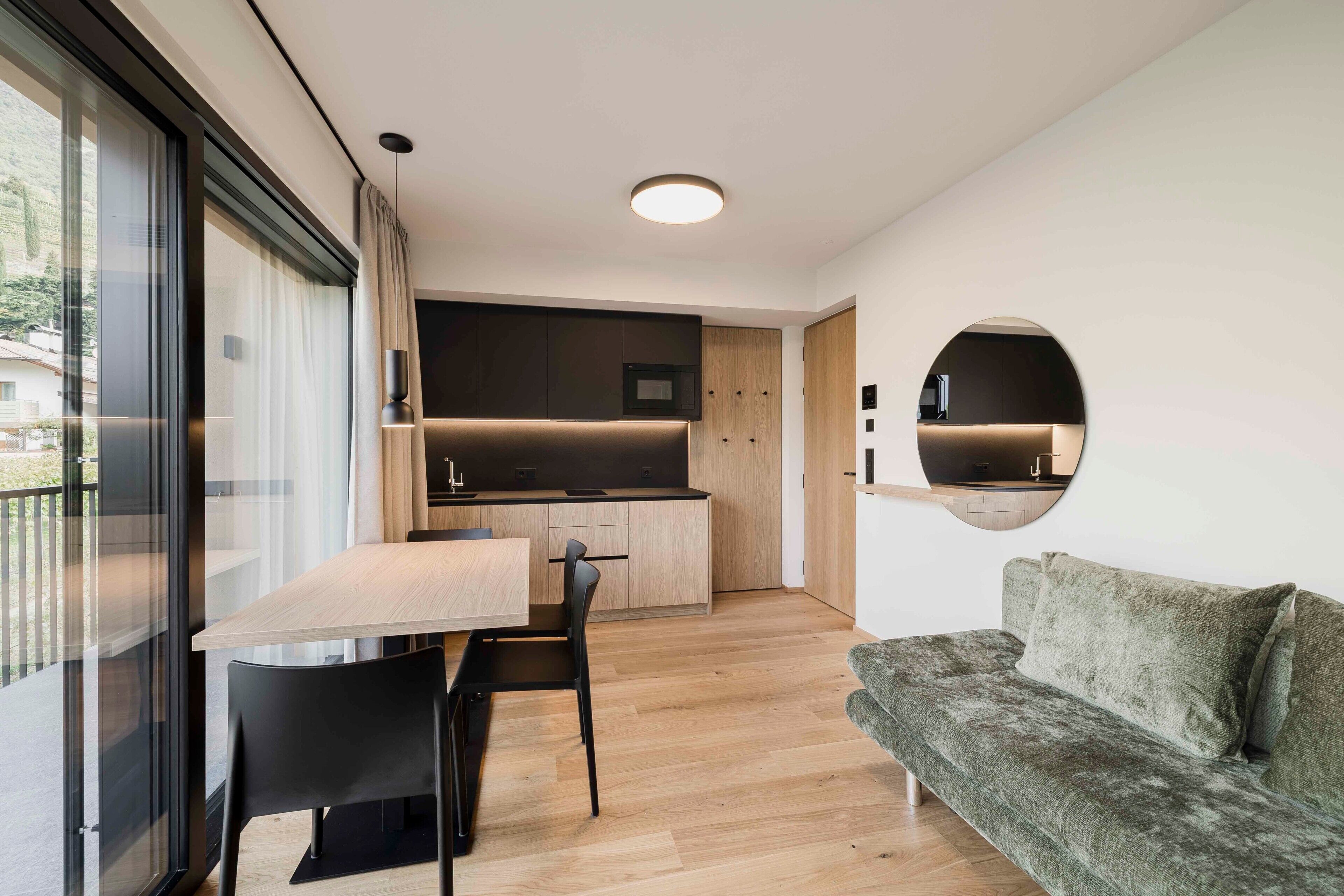 A modern interior with a dining area, kitchen, and a sofa.
