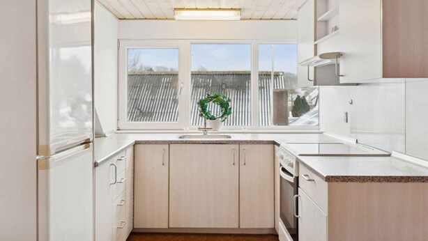 A kitchen with a window, wooden cabinets, and a countertop. - 4 Star Holiday Home in Oksbol (Oksbol)