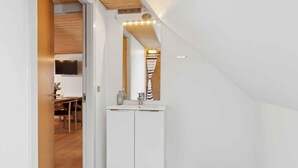 A narrow hallway with a wooden ceiling, a white wall, and a small bathroom with a sink and mirror. - 4 Star Holiday Home in Oksbol (Oksbol)