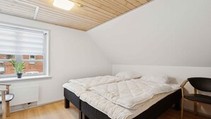A bedroom with a bed, a chair, a window, and a radiator. - 4 Star Holiday Home in Oksbol (Oksbol)
