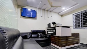 Een moderne receptie met een leren bank, een flatscreen televisie aan de muur en een receptiebalie met de tekst 'TOWNHOUSE'.