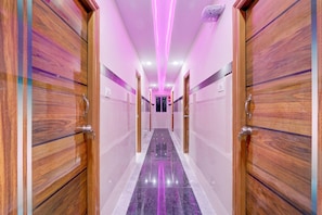 Un corridoio con porte in legno, pavimento in marmo e illuminazione rosa.