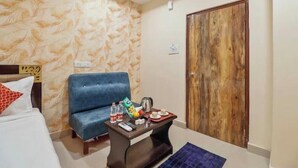 Une chambre d’hôtel avec un lit, un canapé bleu, une porte en bois et une petite table sur laquelle se trouve un plateau avec divers objets.