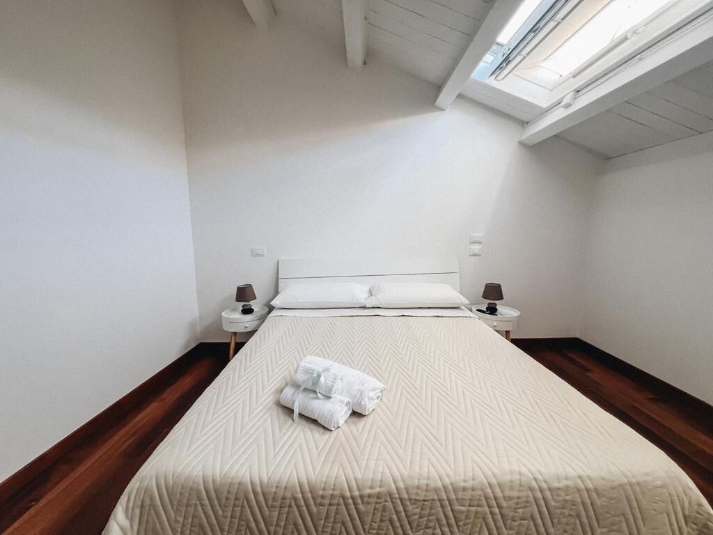 A hotel room with a bed, two bedside tables, a window with a view, and a skylight.