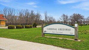 Naamplaatje voor Cardinal Greenway Depot Trail Head, met een heldere lucht en een grasveld op de voorgrond.