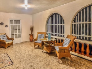 A room with a tiled floor, wooden furniture, a door, and large windows. - Casa Nube (Caguas)