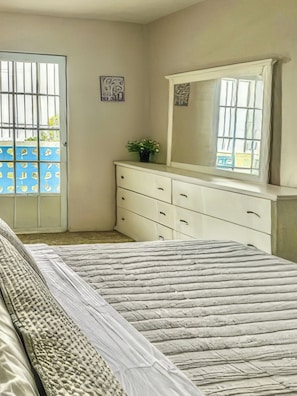 A bedroom with a bed, a dresser, a mirror, and a window with a view. - Casa Nube (Caguas)