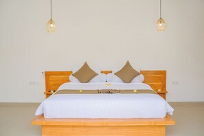 Cama bem arrumada com cabeceira de madeira, duas mesas de cabeceira e duas luminárias pendentes.