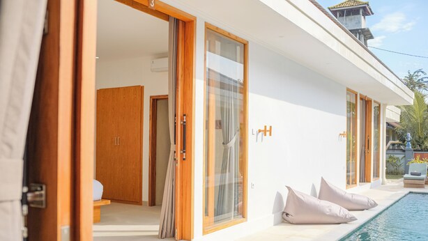 A modern hotel with a swimming pool, wooden doors, and a view of the surrounding area. - Dolphin 2 – Deluxe Double Room in New Villa on Lovina Beach (Buleleng)