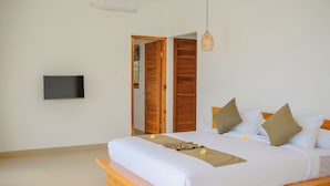 A bedroom with a wooden bed, a television mounted on the wall, and a door leading to another room. - Dolphin 2 – Deluxe Double Room in New Villa on Lovina Beach (Buleleng)