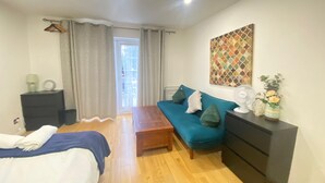A bedroom with a bed, a sofa, a dresser, a fan, and a painting on the wall. - London Luxe 5-bed House Retreat (London)