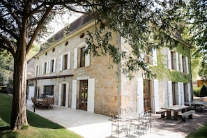 A stone building with a patio area, outdoor furniture, and a tree. - Large Charming House La Rivière, Heated Pool, Sleeps 15 (Calvignac)