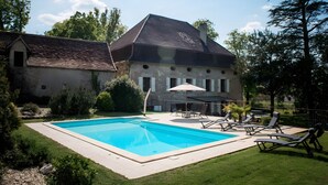 Una casa amb piscina, un pati amb gandules i façana de pedra.