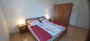 Une chambre à coucher avec un lit en bois, des tables de chevet, une armoire et une porte blanche.