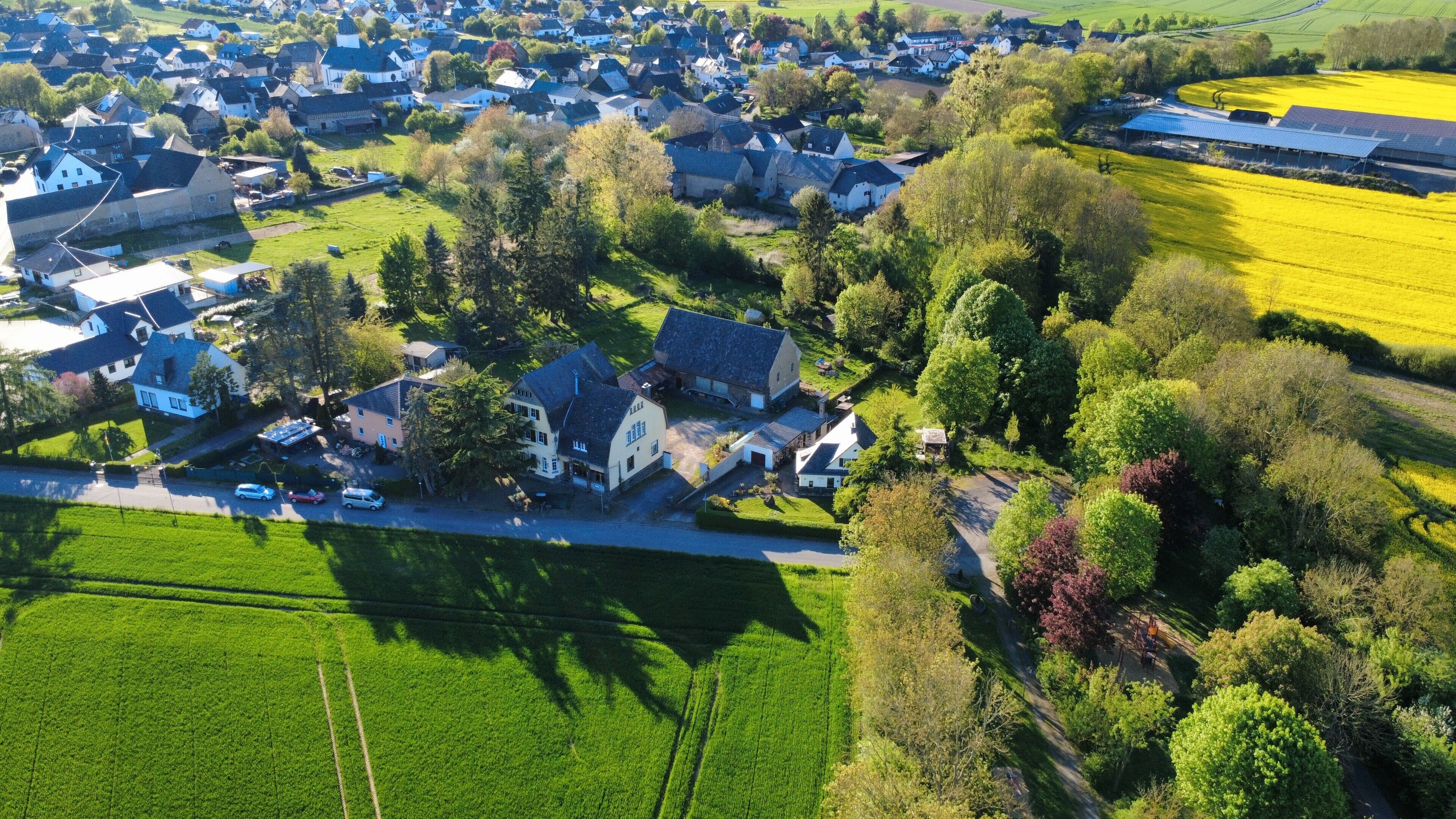 Ein Luftbild einer Wohngegend mit Häusern, grünen Feldern und einer Solaranlage.
