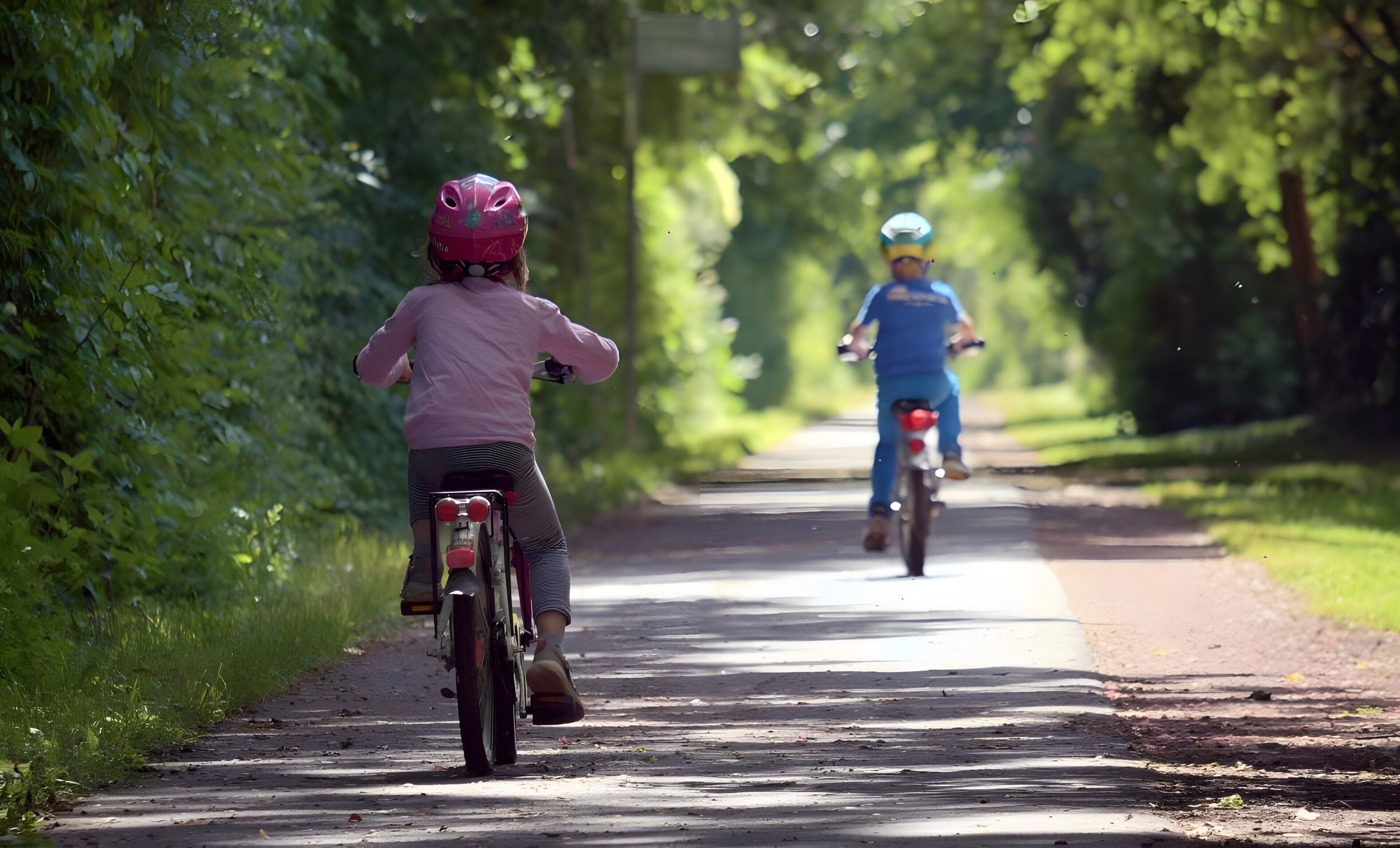 To cyklister på en asfalteret sti omgivet af grønt.