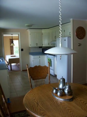 A dining area with a wooden table, chairs, and a kitchen in the background.