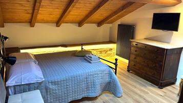 Une chambre à coucher comprenant un lit, une table de chevet, une commode et un téléviseur fixé au mur.