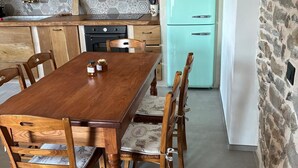 Une cuisine avec un réfrigérateur de couleur turquoise, des armoires en bois et une table à manger avec des chaises.