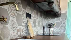 Une cuisine dotée d’un évier en marbre, d’un plan de travail en bois et d’un crédence à motifs.