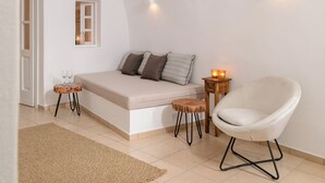 A room with a bed, a chair, a small table with candles, and a window.