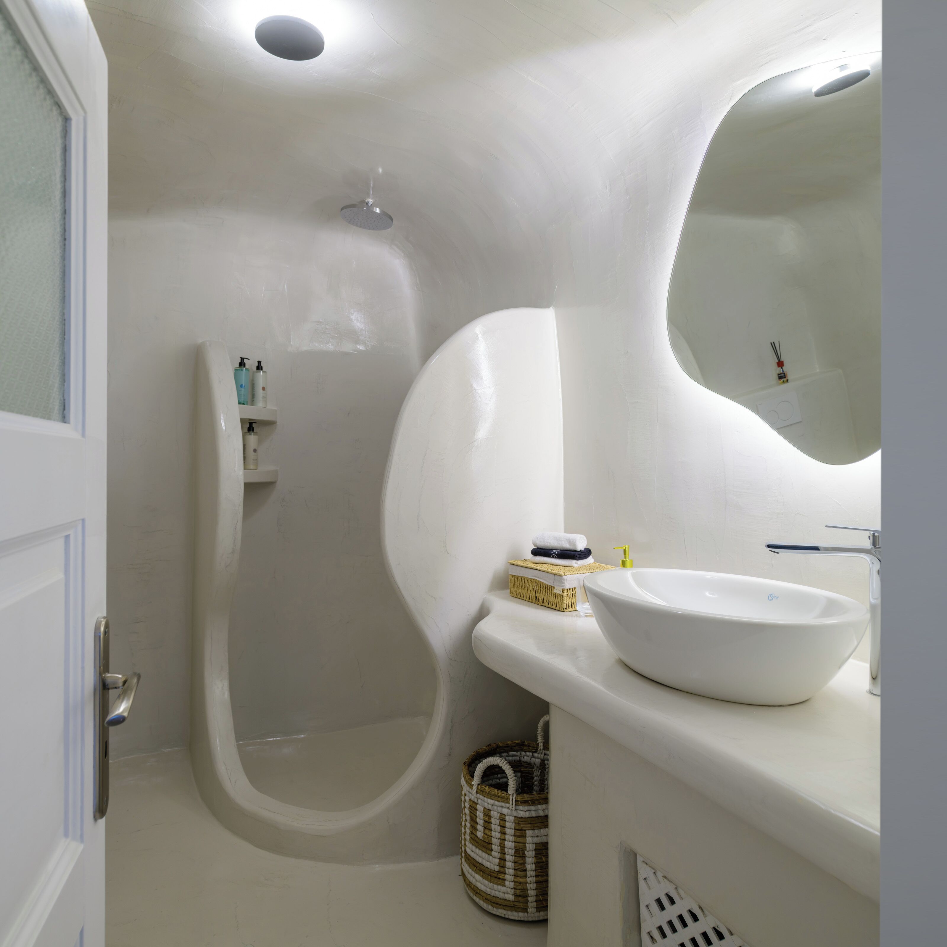 A bathroom with a white sink, a shower, and a mirror.