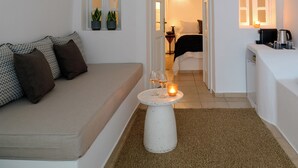 A minimalist living room with a sofa, a coffee table, and a doorway leading to a bedroom.