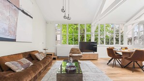 Una sala de estar moderna con un sofá, una mesa de centro y una zona de comedor con sillas.