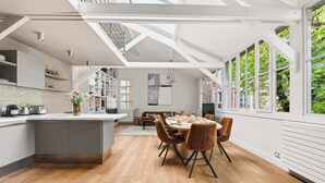 Una cocina moderna con una isla central, suelo de madera y un comedor con mesa redonda y sillas.