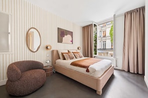 A bedroom with a bed, a chair, a window with curtains, a mirror, and a picture on the wall. - Stylish Central and full of Light Loft - Paris 9th (Paris)
