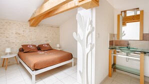 Une chambre à coucher avec un lit, des tables de chevet, un lavabo en verre dans la salle de bain et un miroir.