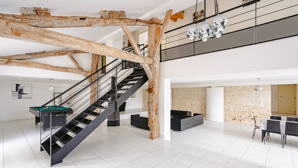 Un intérieur spacieux comprenant un escalier, une table de billard et un coin repas.