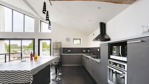 Une cuisine moderne dotée d’un grand îlot central, d’appareils électroménagers intégrés et de grandes fenêtres.