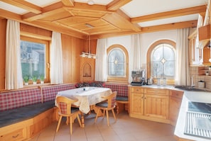A wooden interior with a dining table, bench seating, and a kitchen area.