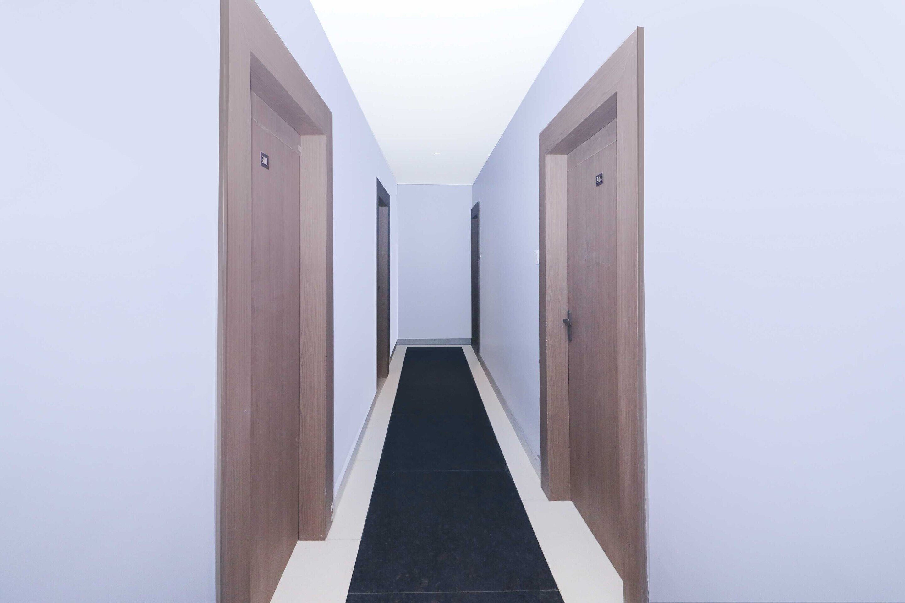 Un couloir étroit, avec des portes en bois de chaque côté et un tapis noir.