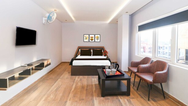 Et moderne hotelværelse med seng, fjernsyn, sofabord, siddeplads og billedkunst på væggen.