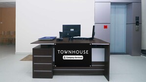 En receptionsdisk med teksten 'TOWNHOUSE', en computer, en blå mappe og en rød alarmknap.