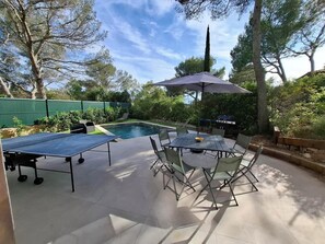 A backyard with a pool, outdoor seating, and a grill.