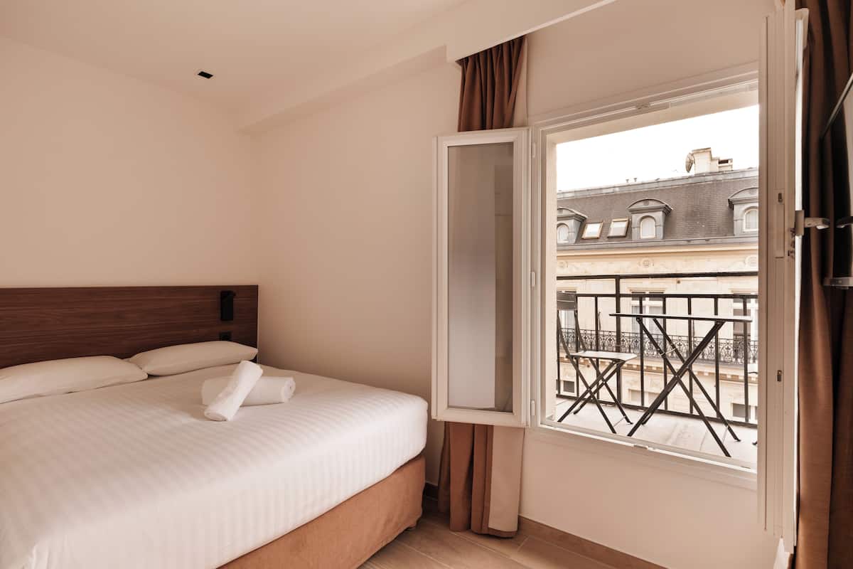 Ein Hotelzimmer mit Bett, Fenster und Blick nach draußen.